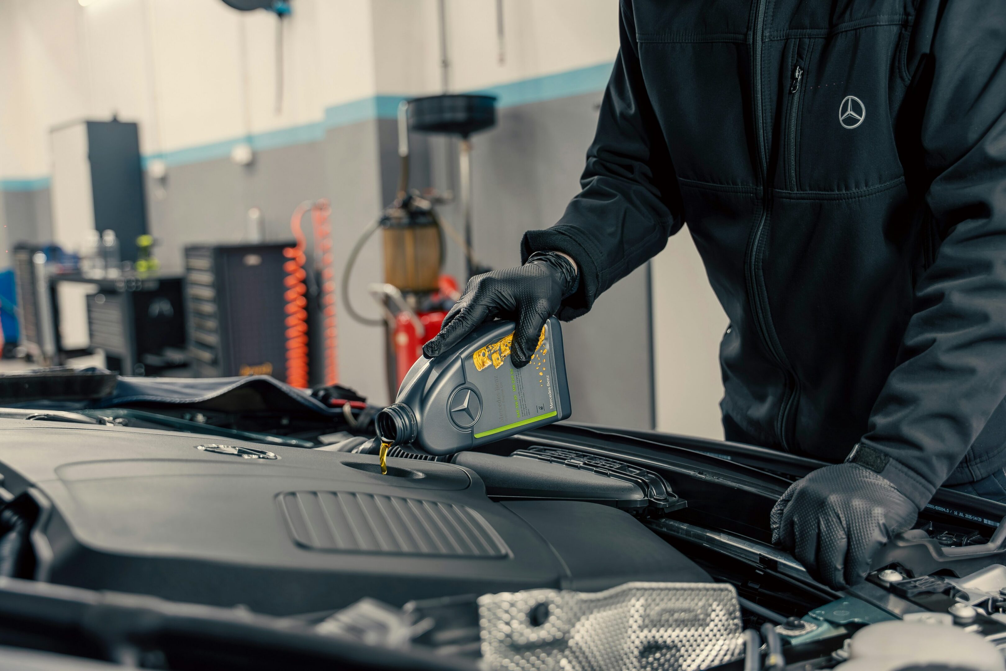 Mechanic pouring motor oil into Mercedes engine