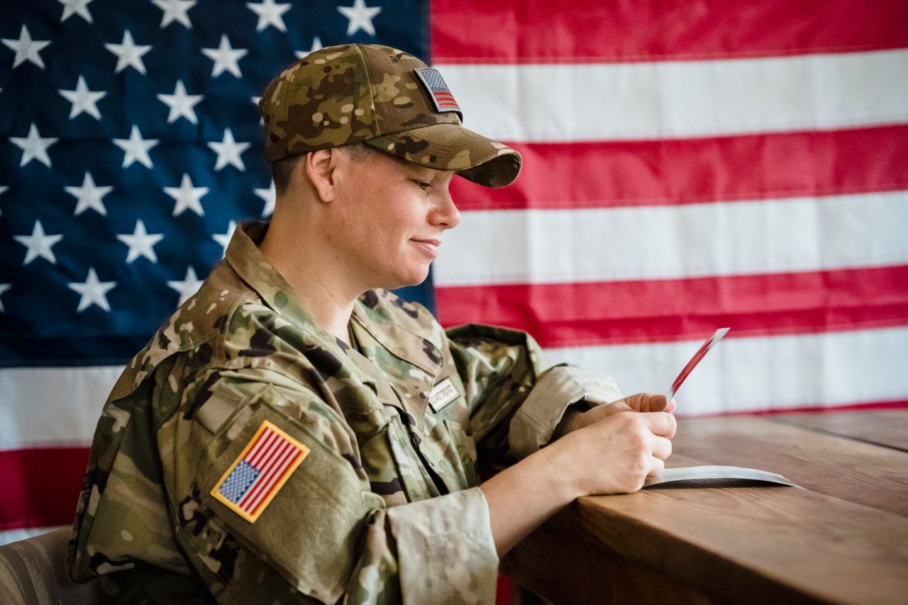 Soldier writing letter with American flag background